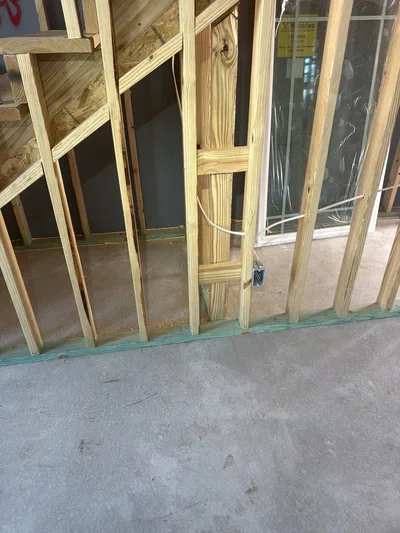 Framed wall on a slab with pressure-treated sole plate; studs above show no visible borate treatment.